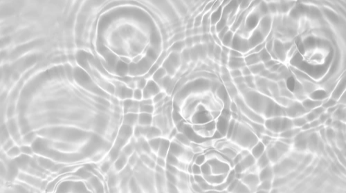 Rippling water surface with circular patterns and reflections, showcasing a calm and serene atmosphere.